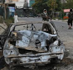Los talibanes al lado de un coche destrozado tras el impacto de misiles contra Kabul, Afganistán, el 30 de agosto de 2021. Foto: AFP