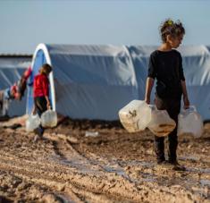 Los niños sirios llevan jarras para llenar con agua en un campamento en las afueras de la ciudad de Al-Hasaka. Foto: AFP 