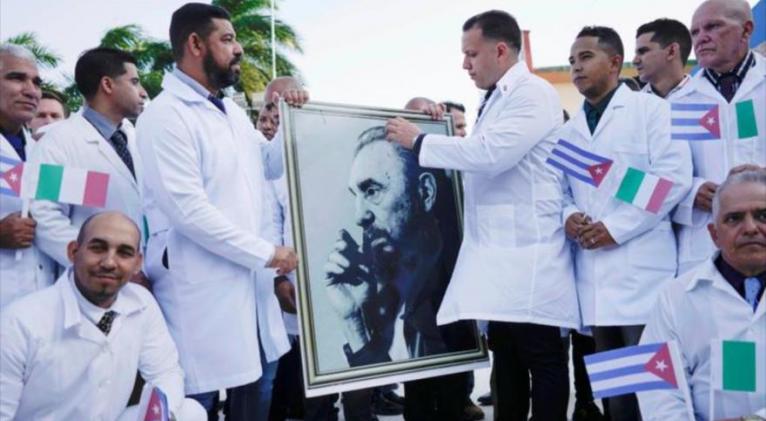 Médicos cubanos sostienen el retrato de Fidel Castro antes de partir al norte de Italia, 21 de marzo de 2020, para tratar pacientes diagnosticados con COVID-19.