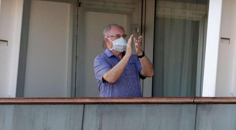 Un pasajero aplaude luego de un anuncio de la tripulacion a bordo del crucero Totterdam el jueves, 2 de abril del 2020, mientras los pasajeros esperan a desembarcar en Port Everglades, Florida. (AP Foto/Wilfredo Lee)