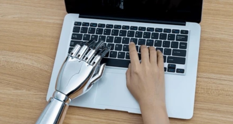 mano humana junto a mano de androide sobre teclado