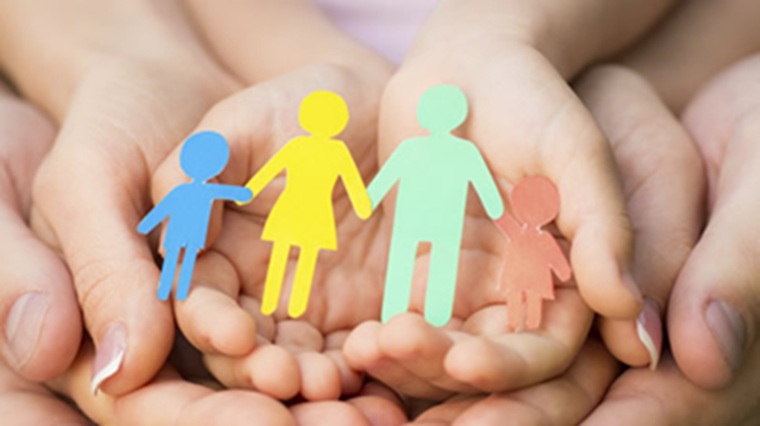 Hand holding paper figures representing a family Hand holding paper figures representing a family