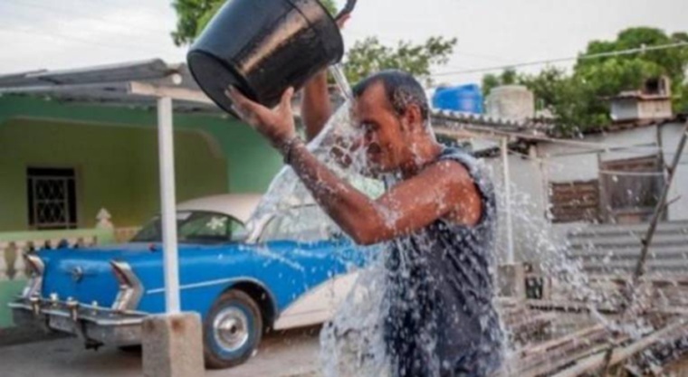 Cuban man pouring a bucket of water over his head because of the heat