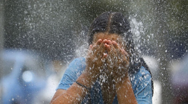 Young woman cooling her face in the heat