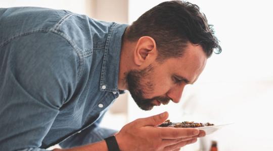 hombre oliendo un plato con alimentos