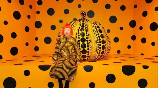 Yayoi Kusama rodeada de lunares, color intenso y una calabaza