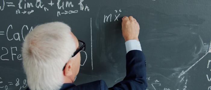 Profesor anciano escribiendo en el pizarrón